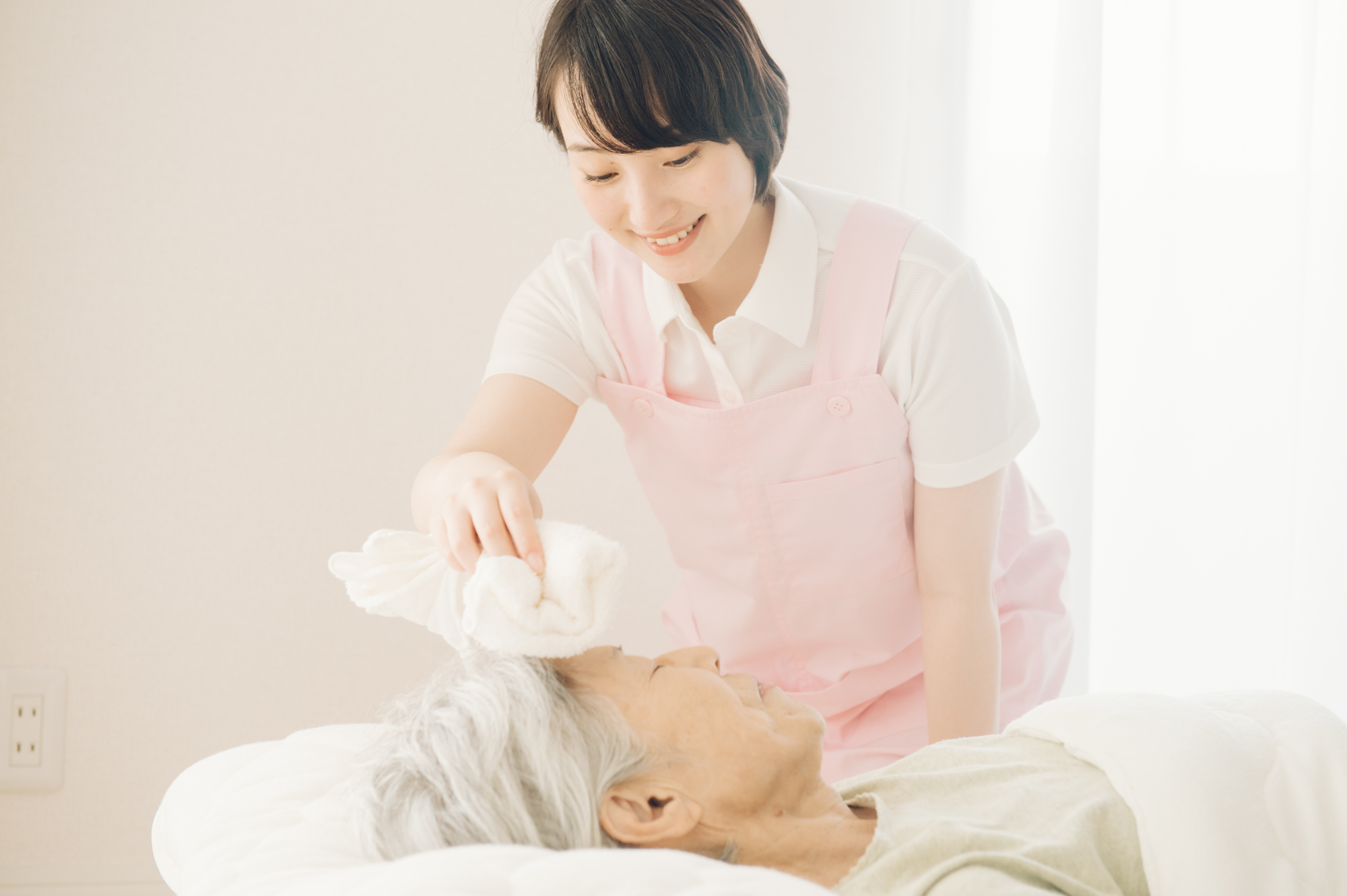 ご自宅のベッドで清拭の介助を受ける利用者様